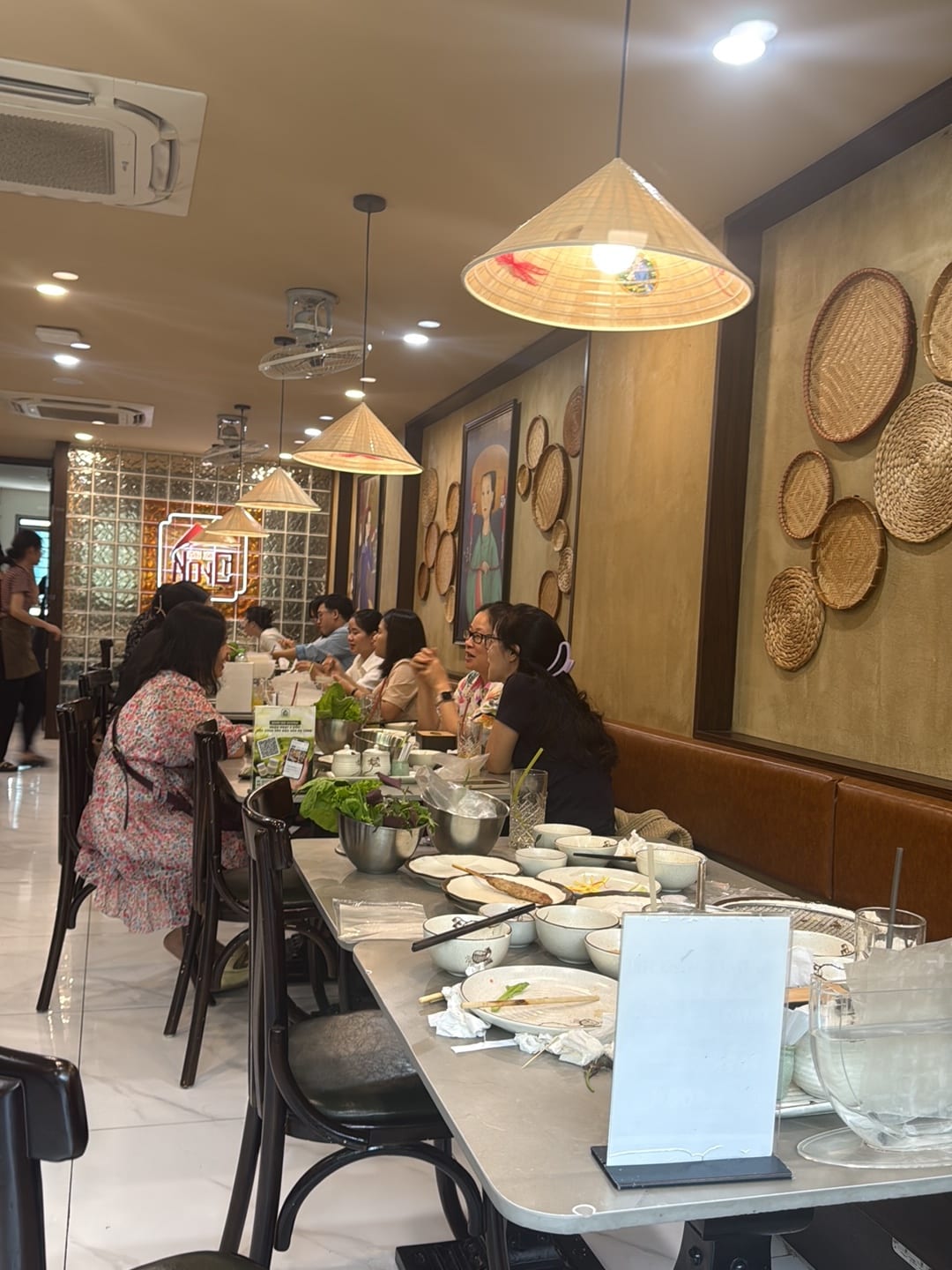Guests dining at long table beneath cone pendant lights